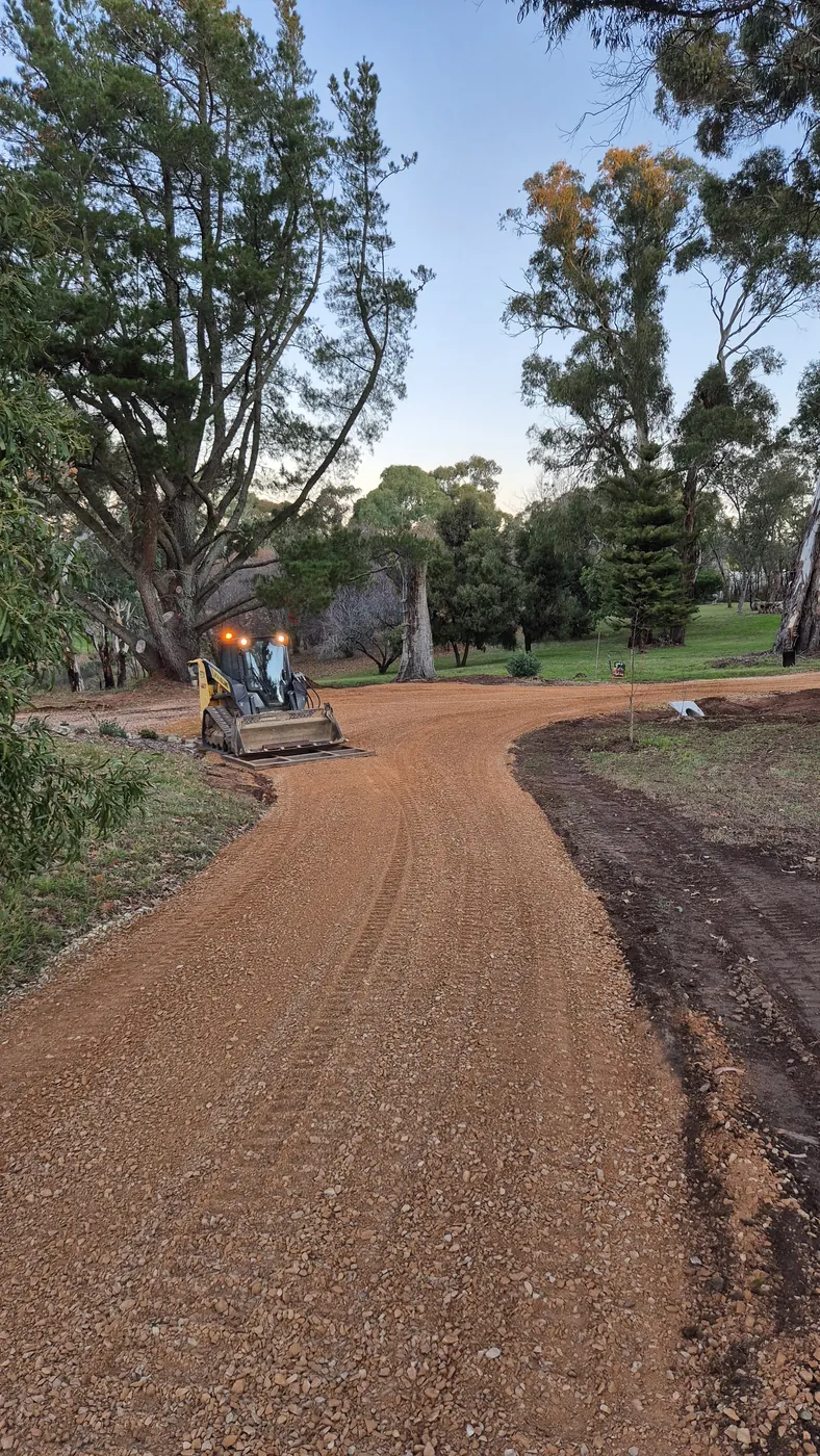 Skid steer finishing a new gravel driveway on a rural property