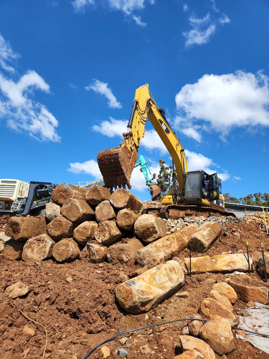EDX excavator placing sandstone boulders for a rock retaining wall